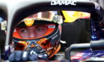 Close-up of a race car driver in a colorful helmet seated in a Formula 1 cockpit, DAMAC branding visible on the halo bar.
