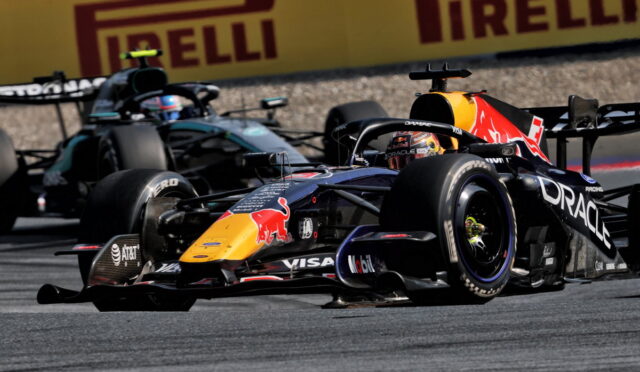 Two Formula 1 cars race side by side on a track, with a Red Bull Oracle-sponsored car in the foreground and a teal Mercedes behind, Pirelli ads in the background.