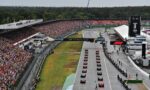 A crowded Formula 1 start line with numerous cars lined up on the grid and a large cheering crowd in the stands.