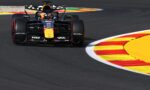 Formula 1 car from Red Bull Racing speeds around a colorful race track curbstone.