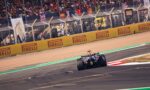 Formula 1 car racing on a track with yellow Pirelli barriers and a cheering grandstand in the background