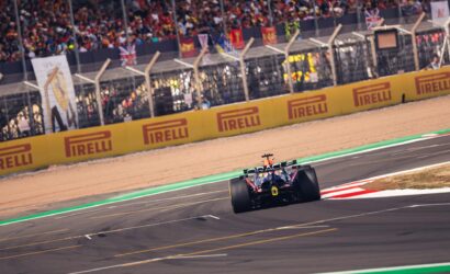 Formula 1 car racing on a track with yellow Pirelli barriers and a cheering grandstand in the background