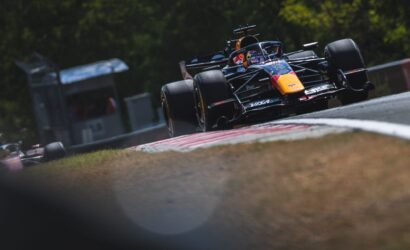 Open-wheel Formula 1 car speeding around a curve on a race track, Red Bull livery and driver in helmet visible.