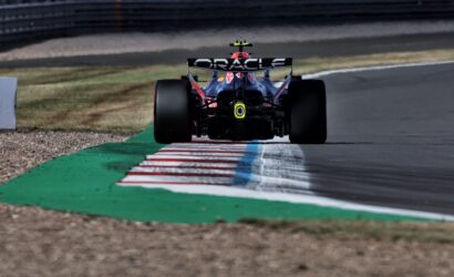 Rear view of a Formula 1 race car on a track, Oracle branding on the rear wing and a striped curb in front.
