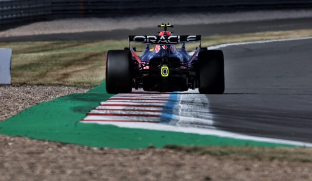 Rear view of a Formula 1 race car on a track, Oracle branding on the rear wing and a striped curb in front.
