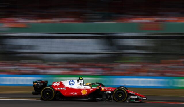 Red Formula 1 car number 44 speeding on a race track with blurred grandstands in the background, motion blur conveying speed.