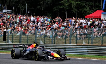Formula 1 car on track with a large, cheering crowd behind a safety fence in the background.