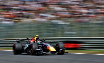 Red Bull Racing Formula 1 car speeding around a bend on a race track with blurred grandstands in the background.