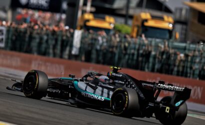 Formula 1 race car labeled Petronas and Microsoft speeding along a race track with a blurred crowd in the background.