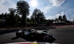 Formula 1 car on a race track with Moët & Chandon banners along the barriers under a bright sun in the sky.