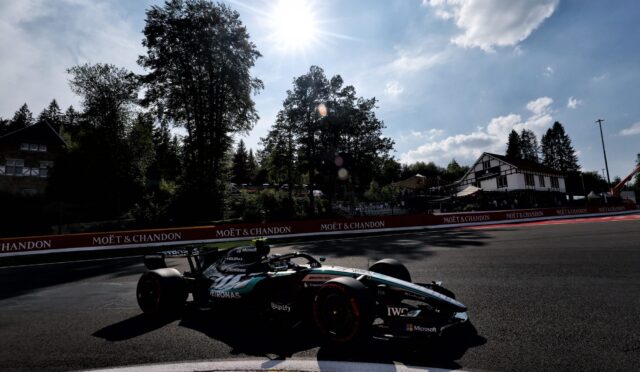 Formula 1 car on a race track with Moët & Chandon banners along the barriers under a bright sun in the sky.
