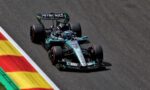 Mercedes‑AMG Petronas Formula 1 car speeding along a race track beside red‑yellow curbs.