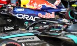 Close-up of race cars side-by-side in a pit area, with prominent Red Bull, Oracle, and Snapdragon branding on the hulls.