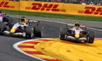 Formula 1 race cars cornering through a chicane with DHL barriers and a cheering crowd in the background.
