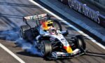 Formula 1 car from Red Bull Racing on a race track, smoke trailing from the tires as it corners past a barrier reading QATAR AIRWAYS.