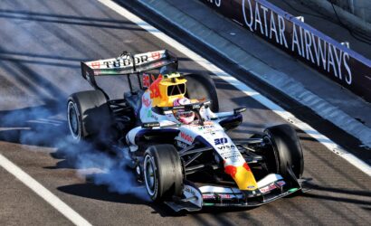 Formula 1 car from Red Bull Racing on a race track, smoke trailing from the tires as it corners past a barrier reading QATAR AIRWAYS.