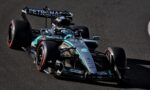 Mercedes-AMG Petronas Formula 1 car on a race track, angled from the front-left, showing black-silver-t turquoise livery and sponsor logos on the chassis and wing.
