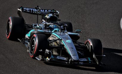Mercedes-AMG Petronas Formula 1 car on a race track, angled from the front-left, showing black-silver-t turquoise livery and sponsor logos on the chassis and wing.