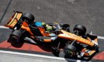 Top-down view of an orange and black Formula 1 car on a race track, seen from above.