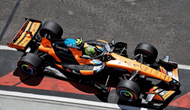 Top-down view of an orange and black Formula 1 car on a race track, seen from above.