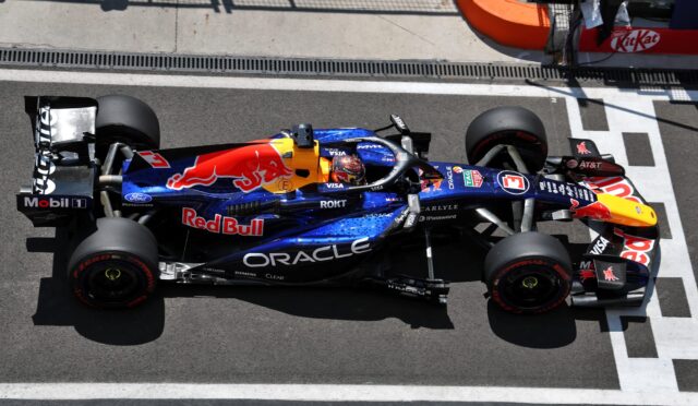Top-down view of a Red Bull Racing Formula 1 car on the pit lane, blue livery with Red Bull logo and sponsor decals like Oracle and Visa.