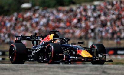 Red Bull Racing Formula 1 car speeds along the track with a large blurred crowd in the background.
