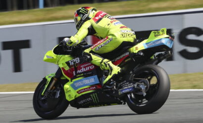 MotoGP rider in a neon-yellow suit leaning into a turn on a race track with a bright yellow bike.