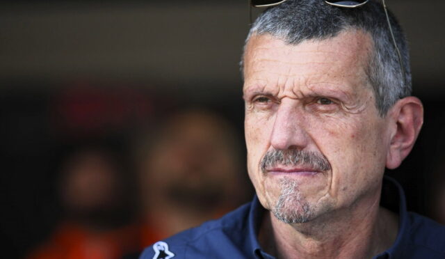 Close-up of a middle-aged man with gray hair and a goatee, sunglasses on his head, looking pensively to the right.