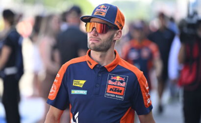 Man in Red Bull KTM Factory Racing polo and cap with mirrored sunglasses at a race event.