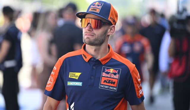 Man in Red Bull KTM Factory Racing polo and cap with mirrored sunglasses at a race event.