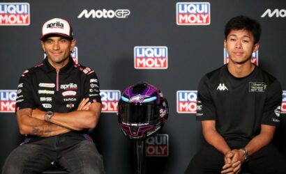 Two MotoGP riders sit side by side with a purple helmet on a stand between them, backdrop shows Liqui Moly and MotoGP logos.