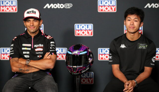 Two MotoGP riders sit side by side with a purple helmet on a stand between them, backdrop shows Liqui Moly and MotoGP logos.