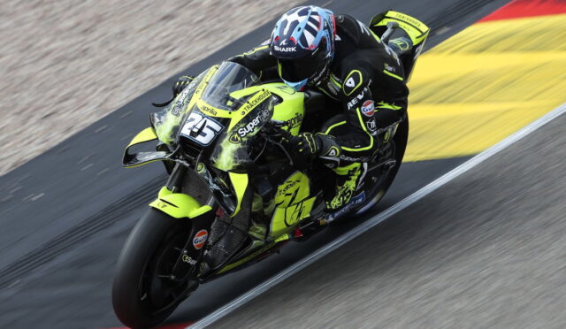 MotoGP rider leaning into a turn on a neon-yellow racing motorcycle on a race track.