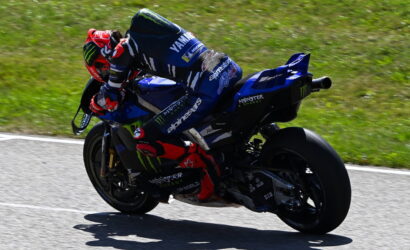 Motorcycle racer in blue Yamaha gear leaning into a curve on a racetrack.