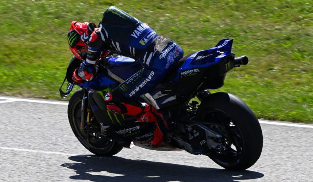 Motorcycle racer in blue Yamaha gear leaning into a curve on a racetrack.