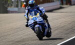 Motorcycle racer in blue riding suit leaning into a left-hand turn on a race track, number 73 visible on the blue bike.