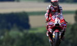 MotoGP rider in a red-and-white suit on a red Lenovo-sponsored motorcycle, number 63, racing toward the camera on a track