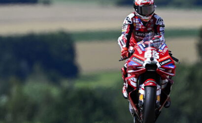 MotoGP rider in a red-and-white suit on a red Lenovo-sponsored motorcycle, number 63, racing toward the camera on a track