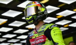 Motorcycle racer in a neon yellow racing suit and full-face helmet with sponsor logos.