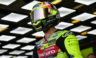 Motorcycle racer in a neon yellow racing suit and full-face helmet with sponsor logos.