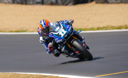 Blue racing motorcycle #36 with rider in blue suit leaning into a left-hand turn on a racetrack