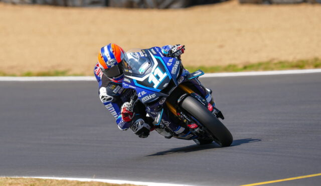 Blue racing motorcycle #36 with rider in blue suit leaning into a left-hand turn on a racetrack