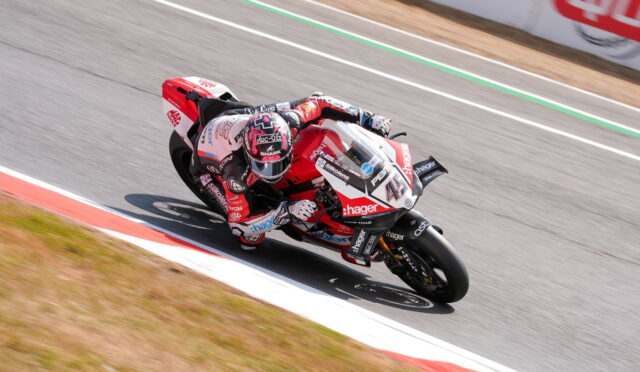 Motorcycle racer in red-and-white gear leaning into a corner on a race track, rider numbered 41 with sponsor logos visible on the bike and suit.