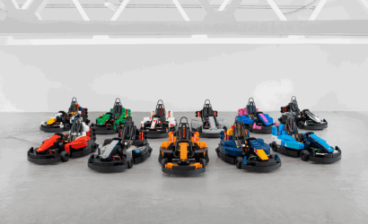 Assortment of colorful go-karts arranged in neat rows on a gray concrete floor in an indoor space.