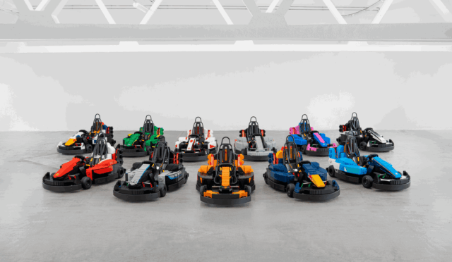Assortment of colorful go-karts arranged in neat rows on a gray concrete floor in an indoor space.