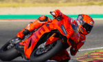 Racer in bright orange suit motorcycle racing into a sharp turn on an orange sport bike.