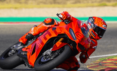 Racer in bright orange suit motorcycle racing into a sharp turn on an orange sport bike.