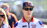 MotoGP rider wearing a Red Bull cap and dark sunglasses, in racing gear with Honda LCR logos.