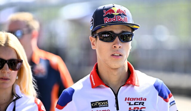 MotoGP rider wearing a Red Bull cap and dark sunglasses, in racing gear with Honda LCR logos.