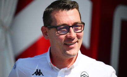 Portrait of a smiling man wearing glasses and a white polo with logos